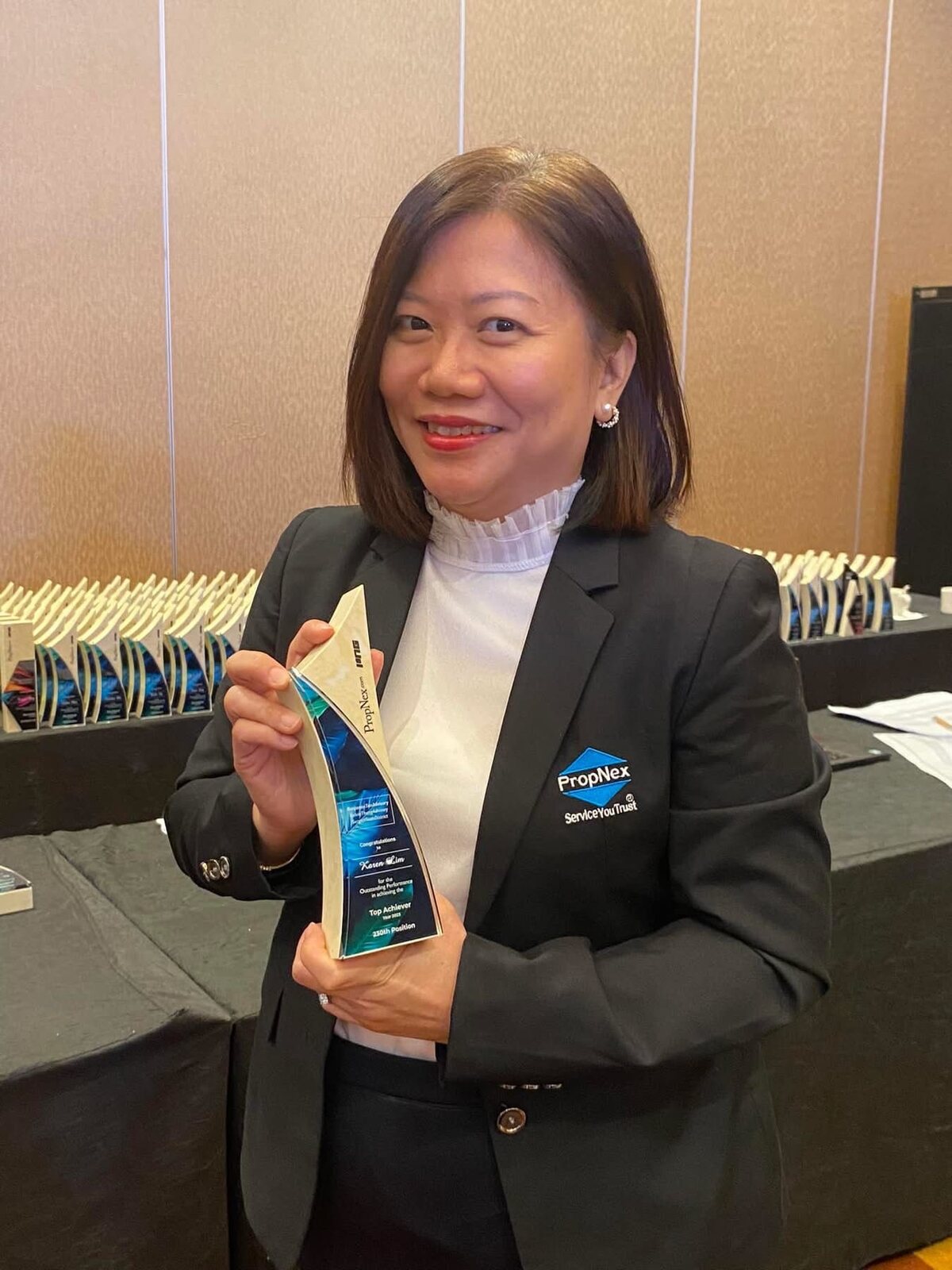 Karen Lim holding her PropNex crystal achievement trophy